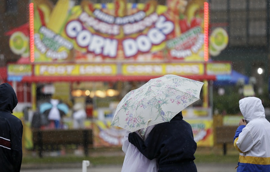 Fairgoers huddle under an umbrella during an afternoon rain shower at the Iowa State Fair, Tuesday, Aug. 18, 2015, in Des Moines, Iowa. (AP Photo/Charlie Neibergall)