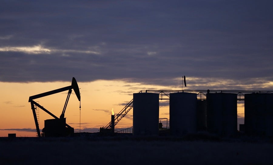 The sun begins to rise behind a pump jack and oil storage tanks, Friday, Dec. 19, 2014, near Williston, N.D. (AP Photo/Eric Gay)